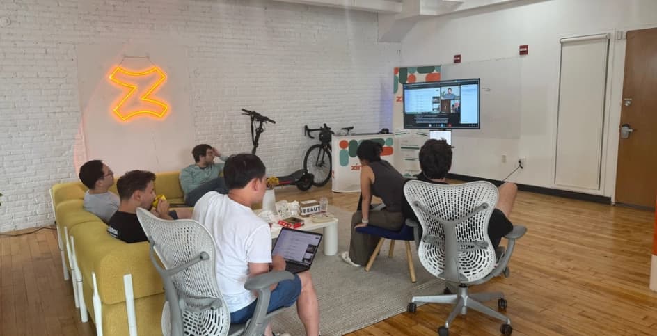 The team watching a live demo under the neon Z in the Soho office